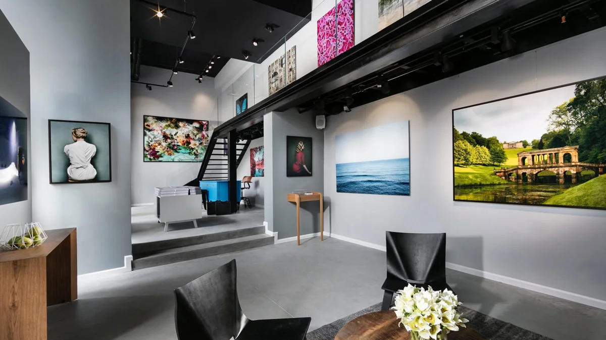 Interior view of a gallery with several works of art on the walls, including photographs and paintings.