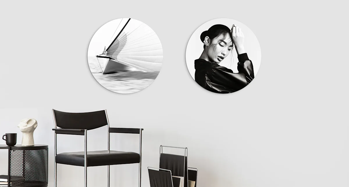 PDP | Round Format & Shapes | Big Picture Slider Section > Round Photo > Slide #2 | Media #1 The motifs of a woman and a sailboat in black and white can be seen on 2 different round pictures that are hung side by side on a wall.
