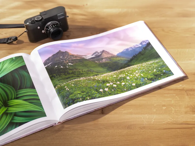 PDP | Bildband | Product Selector Section (US, BE, IT, ES, EU) | Media #1 | Image An open coffee table book lying on a table with a camera next to it
