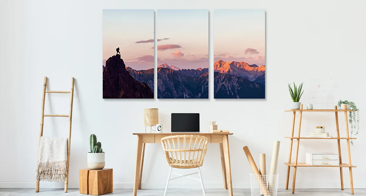 PDP | Multi Panel Wall Art | Big Picture Slider Section > Triptych | Slide #1 | Media #1 A man is standing on a rocky outcrop in front of a mountain panorama. The whole picture is divided into three parts hanging horizontally on the wall.